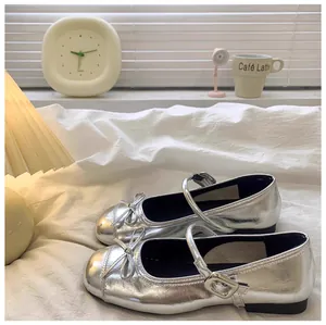 Gedetailleerd overzicht van zilveren Mary Jane-schoenen voor meisjes op een bed.