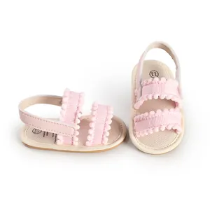 Nahaufnahme von rosa Babysandalen für Mädchen mit dekorativen Pompons und Textilobermaterial