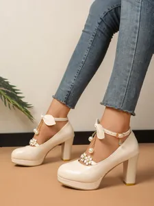 Détail élégant de chaussures à talons hauts beiges avec perles et breloques fleuries