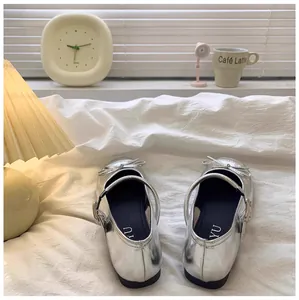 Detailopname van glanzende zilveren Mary Jane prinsessenschoenen voor meisjes op bed