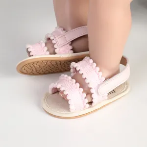 Nahaufnahme von rosa Baby-Lauflernschuhen mit Bommelbesatz und Klettverschluss