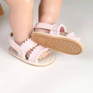 Detailansicht rosa Babysandalen für Mädchen mit Pompon-Besatz und rutschfester Gummisohle