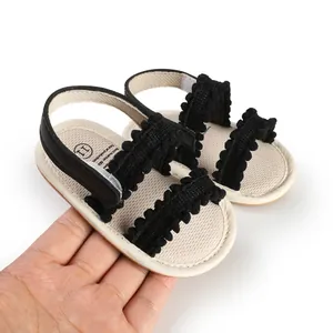 Detailansicht der Baby-Lauflernsandalen mit schwarzem Bommelbesatz und Klettverschluss
