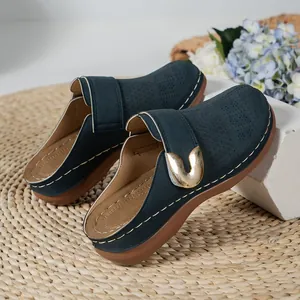 Side view of navy blue thick-soled women's mules with gold buckle and white stitching