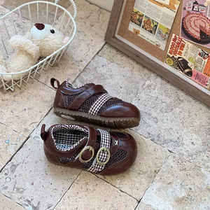 Detailed view of brown breathable mesh baby walking shoes with checkered straps on a stone floor