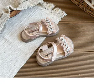 Elegant detail of girls' champagne pearl sandals with ruffles and a velcro strap.