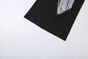 Λεπτομέρεια με ασημένια κρόσσια που λαμπυρίζουν σε ένα μινιμαλιστικό μαύρο φόρεμα