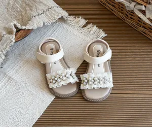 Close-up of white girls' sandals with lace ruffles and elegant pearl flower decorations