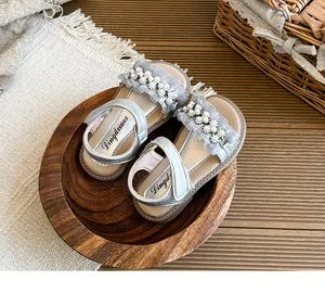 Elegant girls' open-toe princess sandals with pearl and ruffle detailing in a cozy setting.