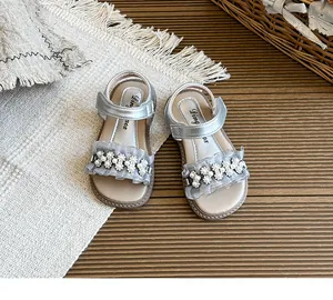 Close-up view of silver girls' open-toe sandals with pearl flowers and ruffle detail