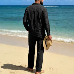 Back view of a man in a black linen long sleeve shirt and pants set on a sunny beach