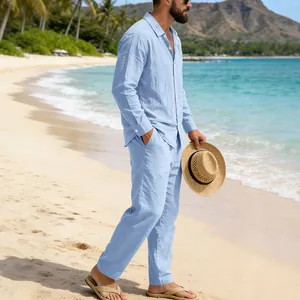 Close-up of a men's light blue linen shirt and trousers set on a beach background.