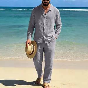 Detailed view of the men's grey linen long-sleeved shirt and matching trousers on a beach.