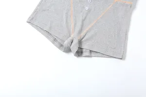 Primo piano di pantaloncini grigi a costine a vita alta con bottoni e cuciture a vista
