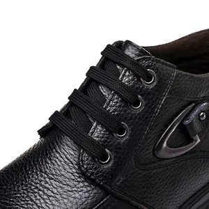 Macro view of premium black leather texture and sturdy lacing on men's high-top snow boots.