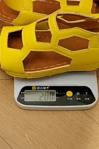 Detailansicht der gelben Keilsandaletten auf einer Digitalwaage mit 200g Gewicht.