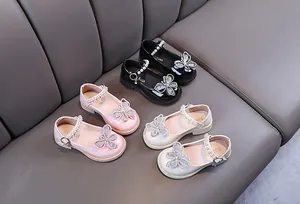 Detalle de zapatos de princesa para niña con mariposa de strass y tiras de perlas.