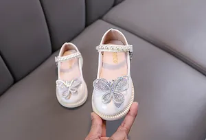 Vista detallada de los zapatos de princesa blancos para niña con mariposa de cristal y perlas