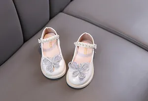 Detalle de zapatos blancos de princesa para niñas con correas de perlas y mariposa