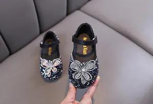 Détail de chaussures de princesse noires pour filles avec strass brillants et papillon