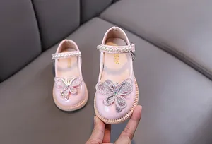 Detalle de zapatos de princesa rosas para niña con mariposa de pedrería y perlas