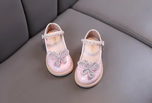 Vista detallada de los zapatos de princesa rosas para niña con mariposa de pedrería y perlas