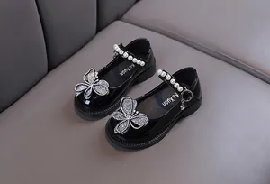 Primer plano de zapatos de princesa para niña en charol negro con mariposa de strass
