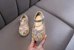 Détail de chaussures de princesse dorées pour filles avec nœud papillon en strass