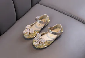Détail de chaussures de princesse dorées pour filles avec ornements papillon strass