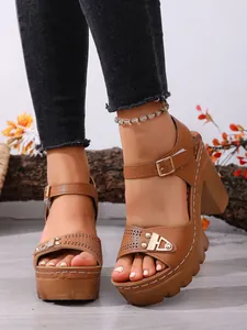 Nahaufnahme brauner Damen-Plateausandalen mit Blockabsatz, Fesselriemen und Laserschnitt-Muster.
