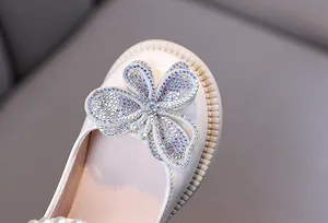 Primer plano de mariposa con pedrería en zapatos de princesa para niñas.
