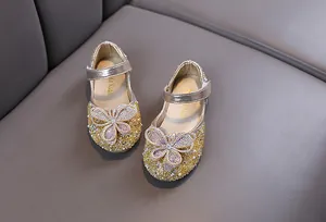 Gros plan de chaussures de princesse dorées pour filles avec détails de papillons en strass