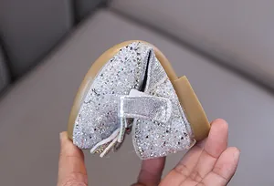 Gros plan montrant la semelle souple des chaussures de princesse argentées pour filles