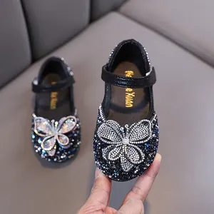 Chaussures de princesse noires pour filles avec grand papillon en strass étincelant.