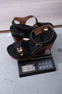 Detailansicht schwarzer Sandalen mit Blockabsatz auf einer Waage mit 364,5 Gramm Gewicht