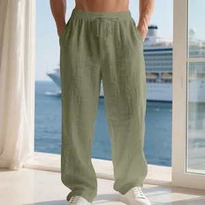 Pantalon en lin vert olive pour homme, coupe ample, dans un décor de croisière ensoleillé.