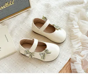 Detailansicht von cremefarbenen Mädchen-Mary-Jane-Schuhen mit karierten Schleifen