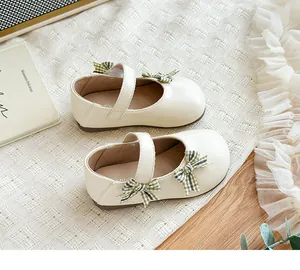 Nahaufnahme von eleganten cremefarbenen Kleinkind-Mary Janes mit grünen Karoschleifen