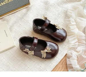 Nahaufnahme brauner Mädchen-Prinzessin-Schuhe mit karierter Schleife und Klett
