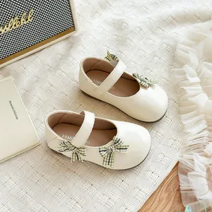 Elegante cremefarbene Mary Jane Schuhe für Mädchen mit grünen Karoschleifen-Dekorationen.