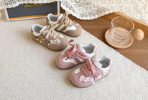 Vue détaillée de baskets pour enfants avec des nœuds à carreaux en rose et marron