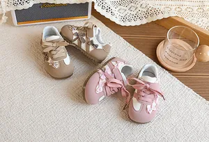 Gros plan de chaussures GAT pour enfants avec nœuds à carreaux roses et marron.