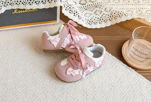 Gros plan de baskets roses pour enfants avec des nœuds à carreaux et détails blancs.