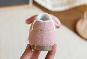 Gros plan du talon en daim rose sur des baskets pour filles avec semelle gomme et nœud