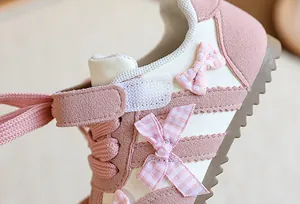 Vue détaillée des nœuds roses à carreaux et de la texture en daim de ces baskets filles