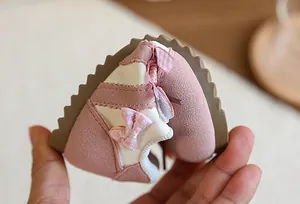 Gros plan montrant la souplesse et la texture d'une basket rose pour fille avec nœud.
