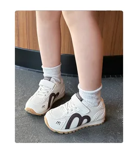 Detailed view of breathable white kids sneakers featuring brown M-shaped accents and gum sole