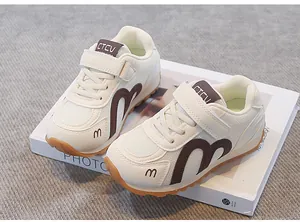 Detail view of breathable mesh kids sneakers in beige and brown with Velcro straps.