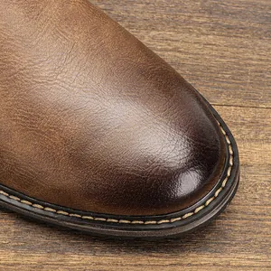 Close-up of burnished brown leather shoe toe showing fine texture and welt stitching.