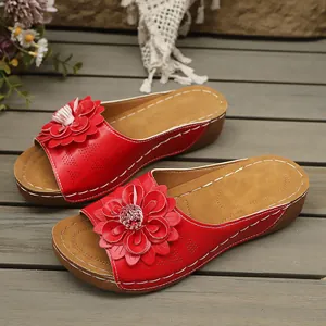 Detalle de sandalias de cuña rojas para mujer con elegante decoración floral 3D.